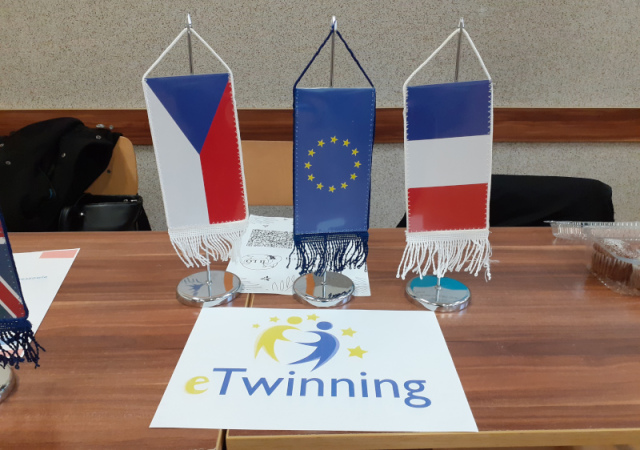 na stoliku stoją flagi: Czech, Unii Europejskiej oraz Francji wraz z logo eTwinning. 